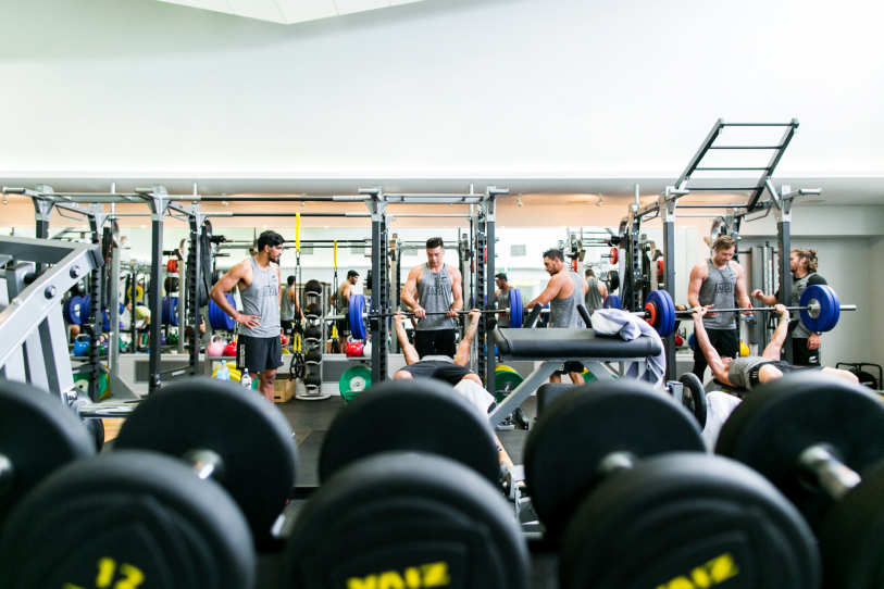 View of athletes training in the gym from behind some barbells 