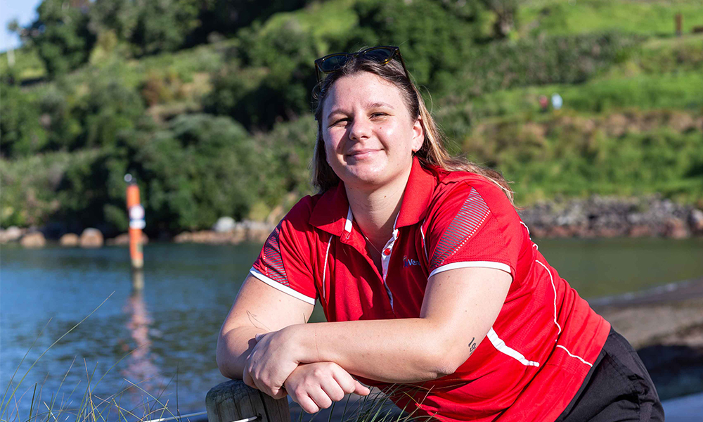 Mount Hot Pools lifeguard leaning on fence in front of Mount Maunganui